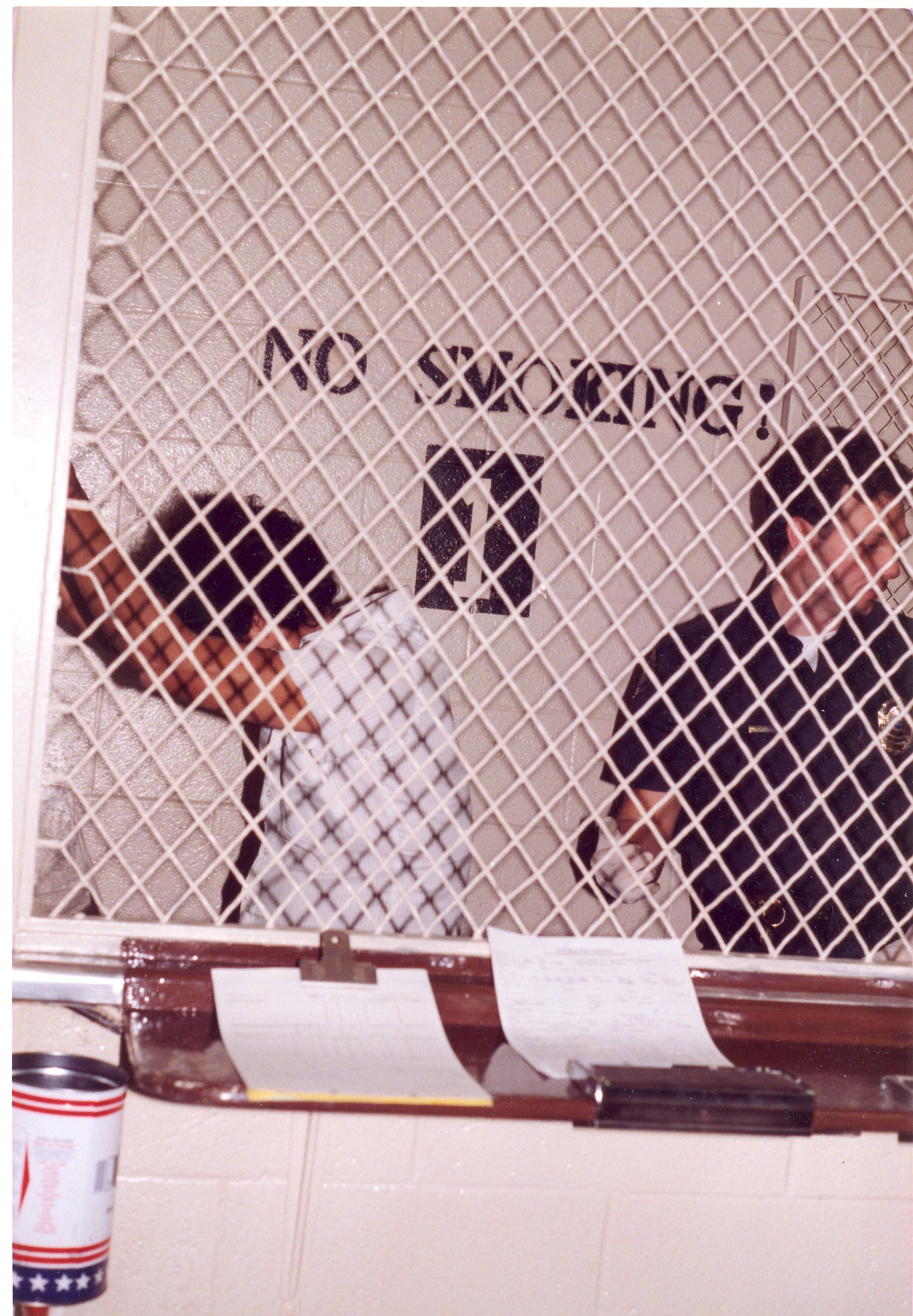 Corrections Officer Wagner (right) is in the booking cage with a criminal. He was a jailer for two years, and learned much about the criminal mind.