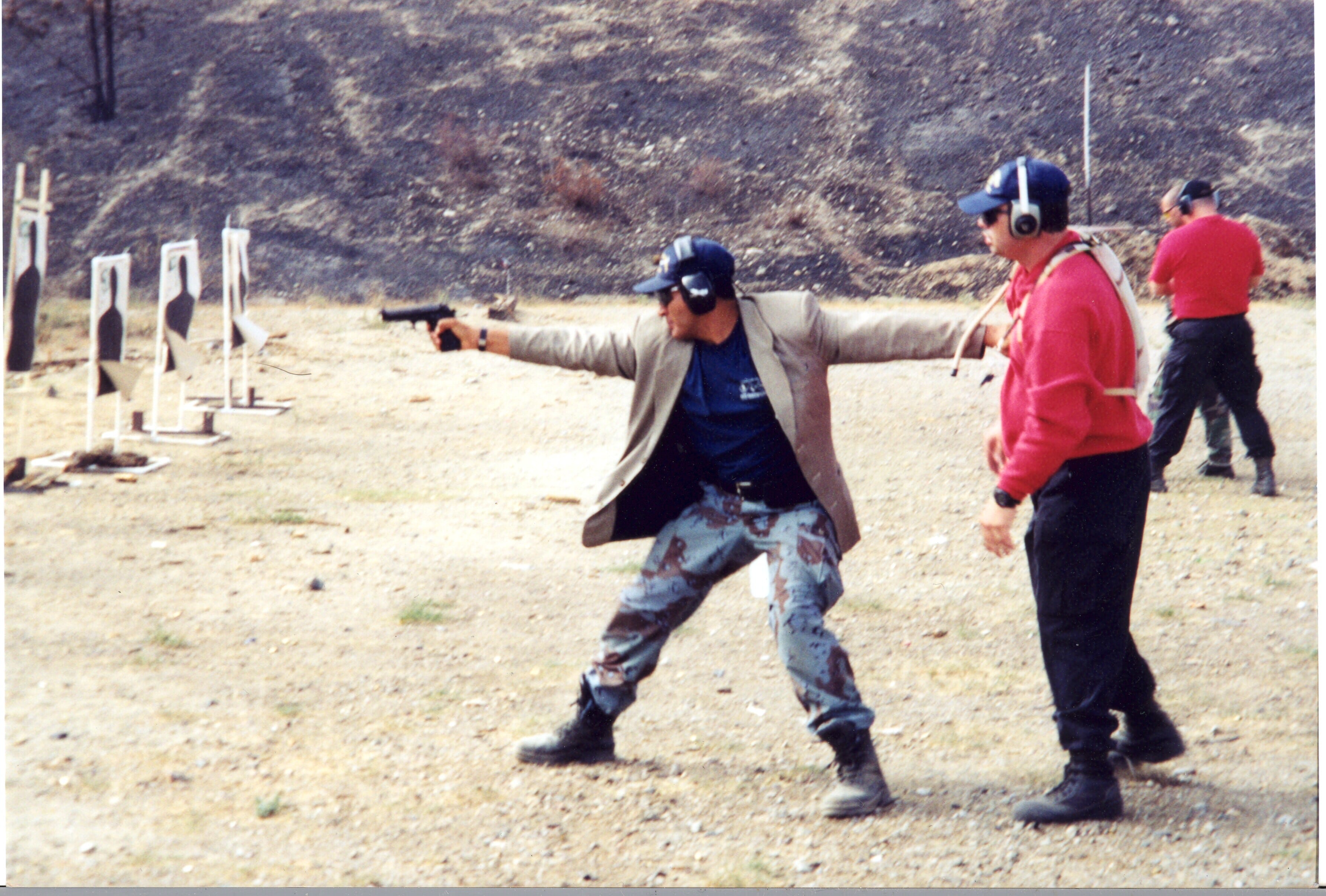 Jim (in red), playing the role of a principal, is being protected by a law enforcement officer on a live-fire range.